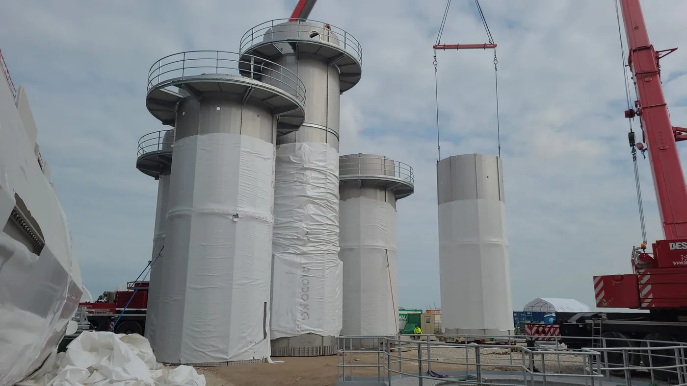 Stainless steel chimney sections laid out on site before installation at a French potato factory