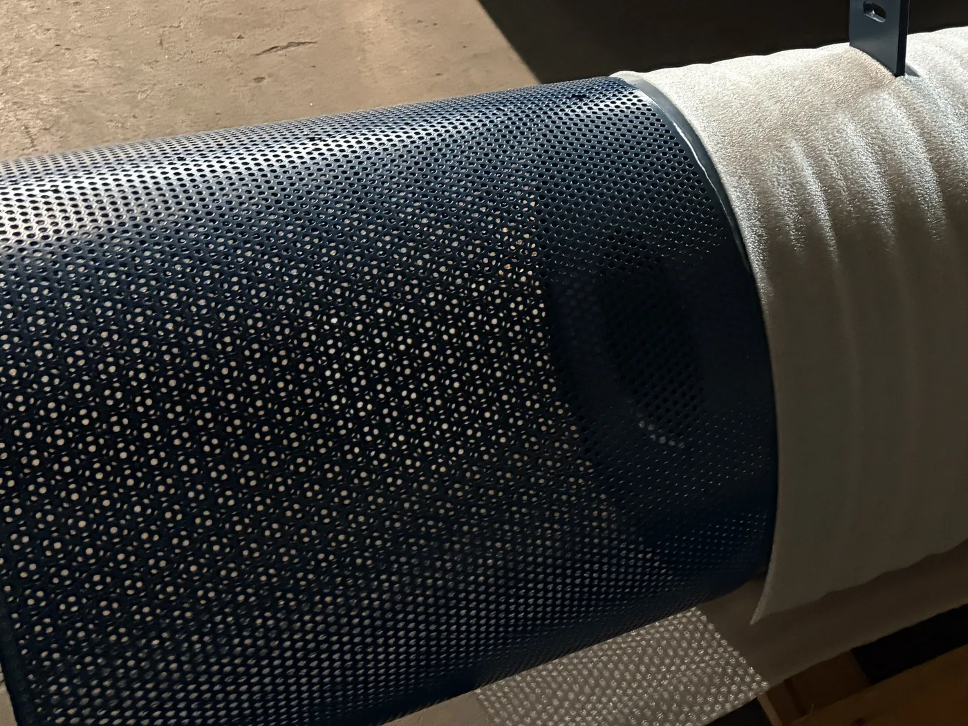 Perforated intake section of a blue blower inlet silencer, partly wrapped in protective foam